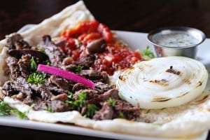 Babylon Café’s beef shawarma is piled on flatbread and ready to drizzle with tzatziki and eat like pizza.