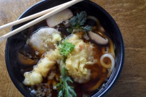 Umami-rich shrimp tempura atop toothsome udon noodles in a steaming bowl of veggie broth.