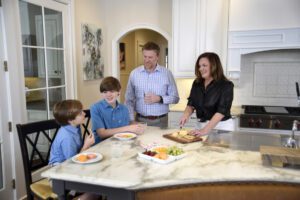 The Carlisle family pauses for a snack around their kitchen island, which features a built-in banquette.