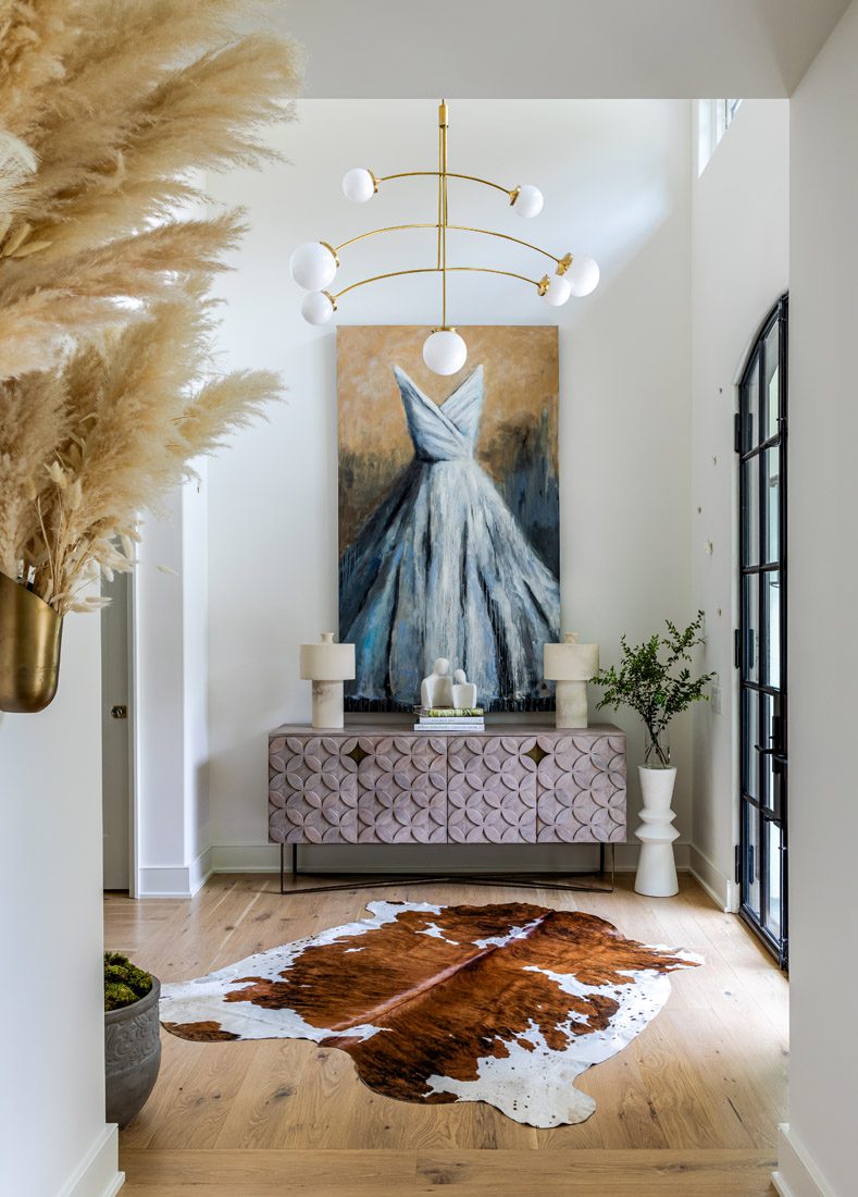 A custom dress painting by Carylon Cooper, gifted to Susan from her husband on their first Christmas in the house, presides over the sunlit foyer.