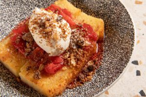 Juicy preserved strawberries crown the seared milk cake, providing a sweet finale to any meal.
