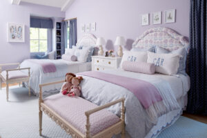 Headboards in the girls' bedroom are covered in a Schumacher fabric, and the walls are painted lilac.