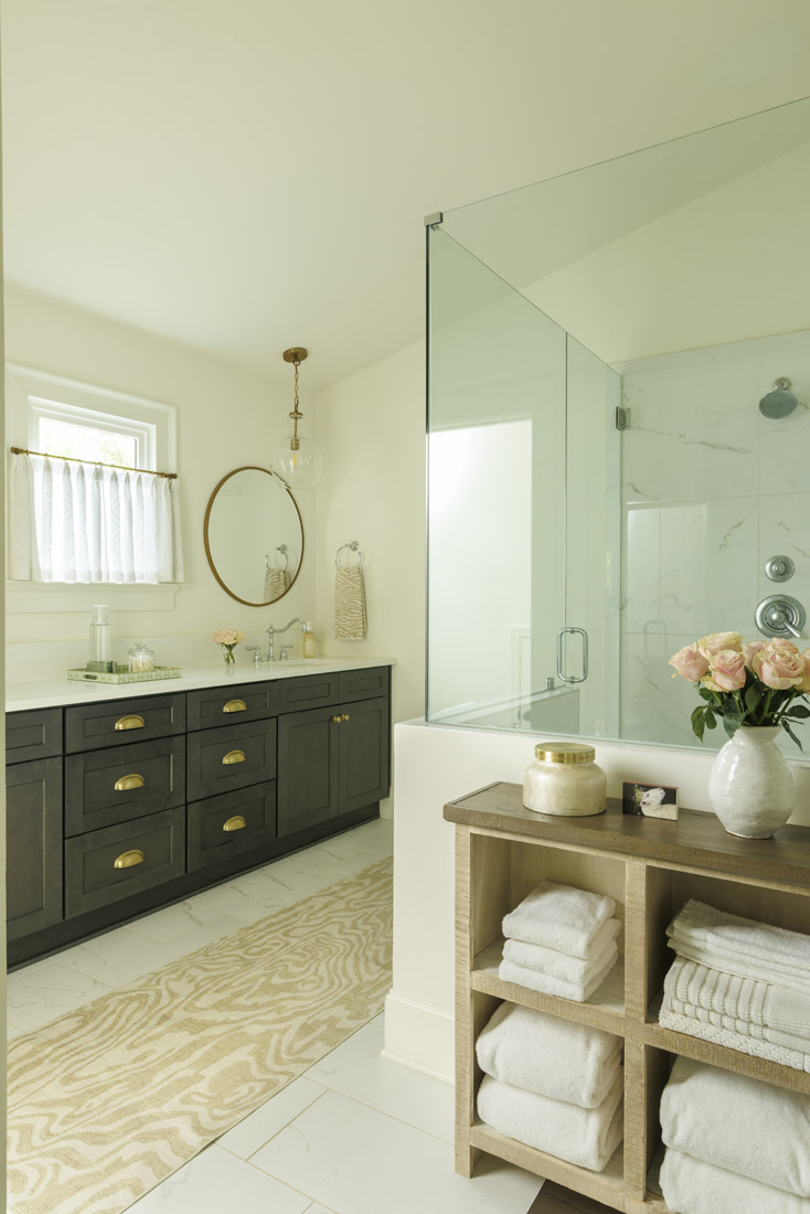 The serene primary bathroom features cafe curtains in a linen-blend sheer material from Weitzner Fabric.