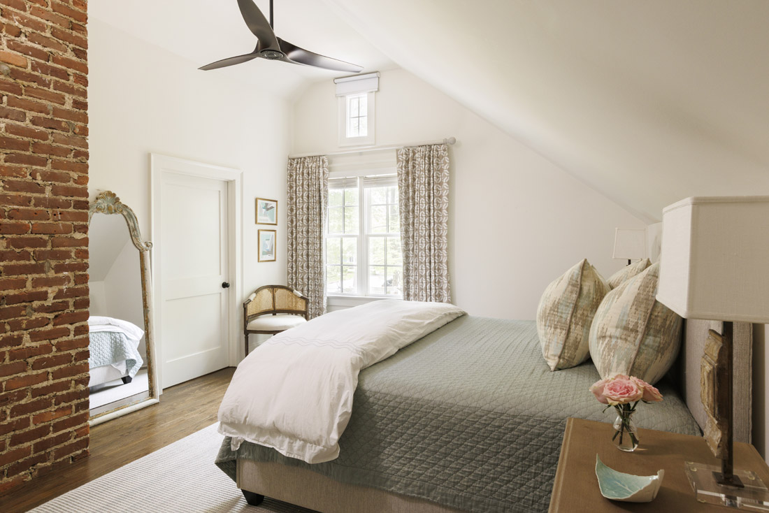 The primary bedroom features tan and white curtains in Fabricut Trend appliquéd fabric, Gramercy linens and custom throw pillows.