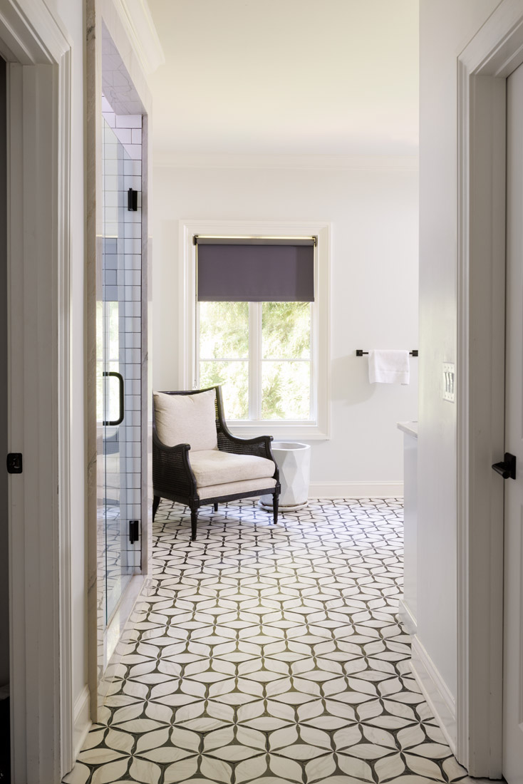 Black and white flooring in the primary bathroom continues the neutral palette of the suite.